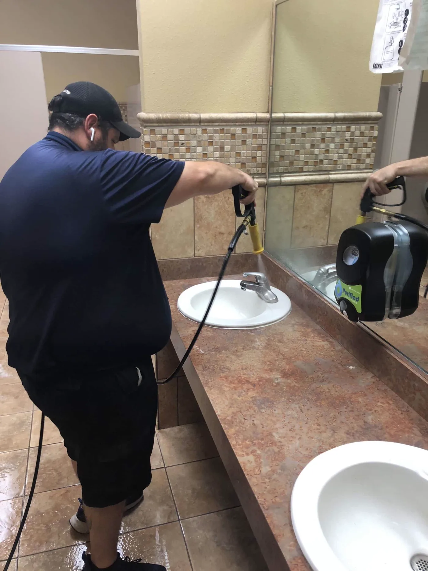 Purified Solutions technician performing restroom sanitation service on-site